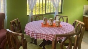 Ein Essbereich mit einem runden Tisch, bedeckt mit einer karierten Tischdecke, umgeben von Holzstühlen mit gepolsterten Sitzen.