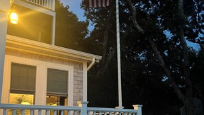 Une maison avec une clôture blanche en bois, un balcon et un mât sur lequel flotte le drapeau américain.