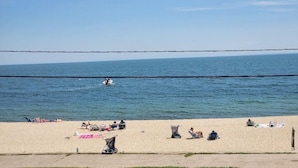 Une plage où des gens se détendent, un bateau sur l’eau et un ciel dégagé.
