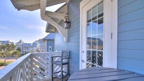 A wooden deck with a railing, a chair, and a glass door leading to a covered area. - Corner, 3rd-Fl Pet-Friendly Condo w/ 2 Decks@Cinnamon Shore+Great Amenities! (Port Aransas)