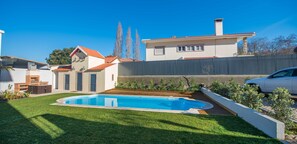 Un jardin arrière aménagé pour une maison d’habitation, avec une piscine, un espace barbecue et un jardin clos.