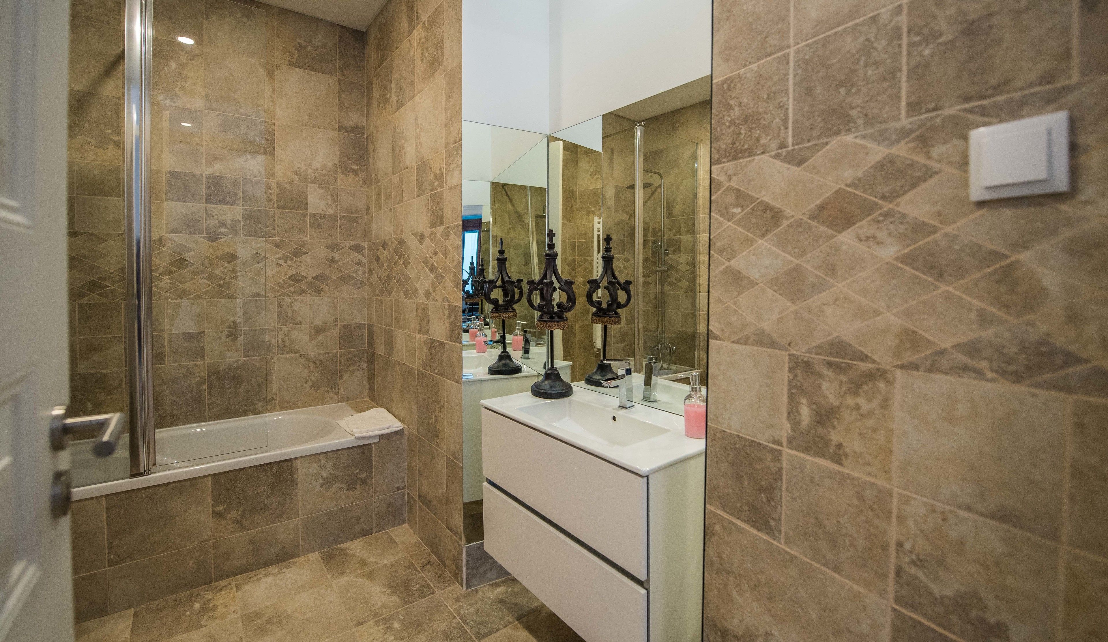 A modern bathroom with a glass shower enclosure, a white vanity with a mirror, and decorative candle holders.