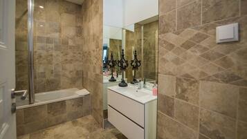 A modern bathroom with a glass shower enclosure, a white vanity with a mirror, and decorative candle holders.