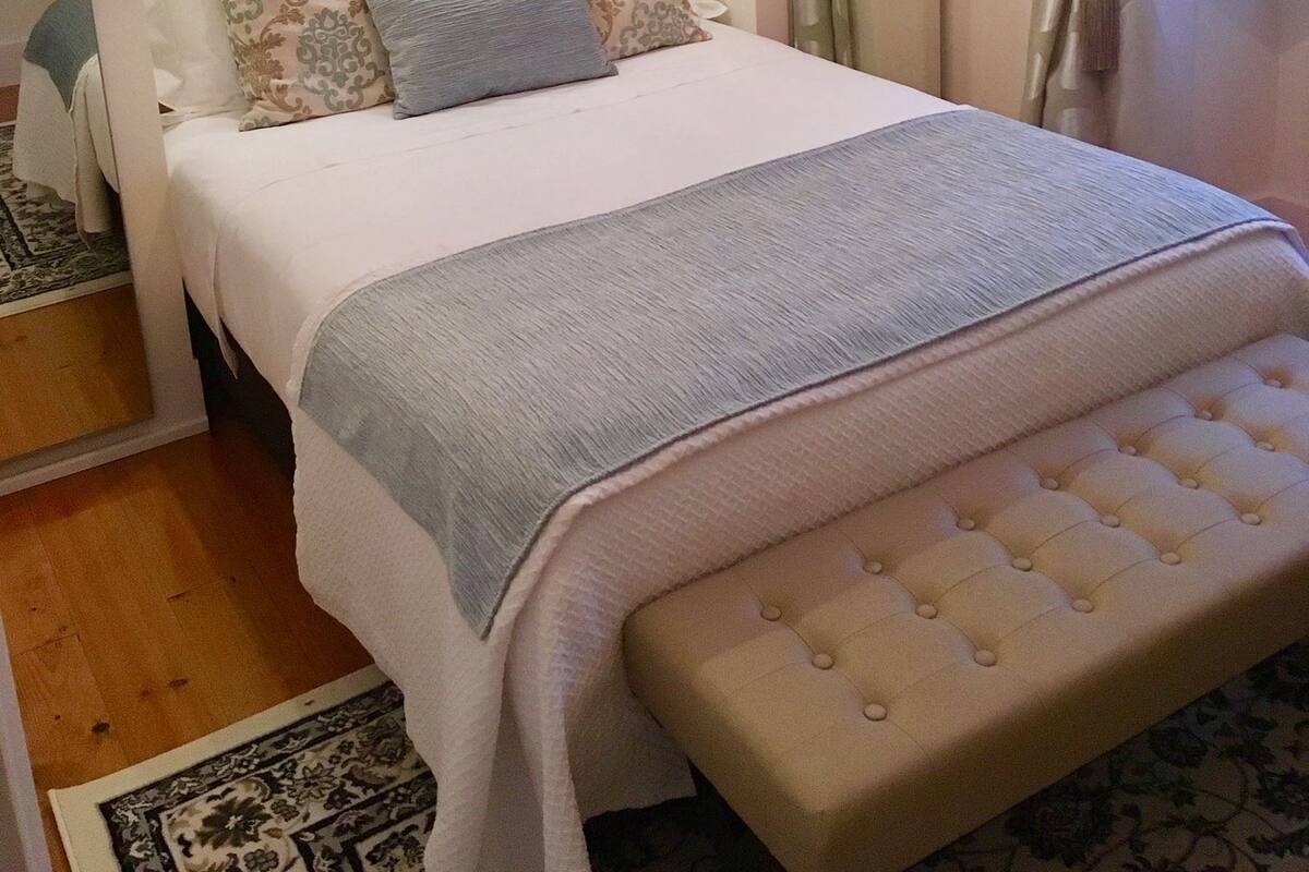 Une chambre à coucher bien rangée, avec un lit, une table de chevet et un miroir.