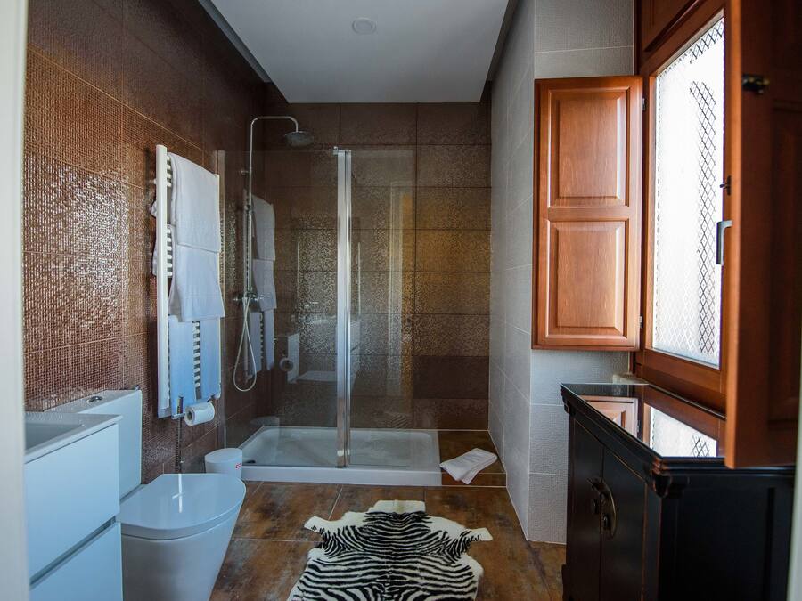 A modern bathroom with a glass-enclosed shower, a bathtub, and a toilet.