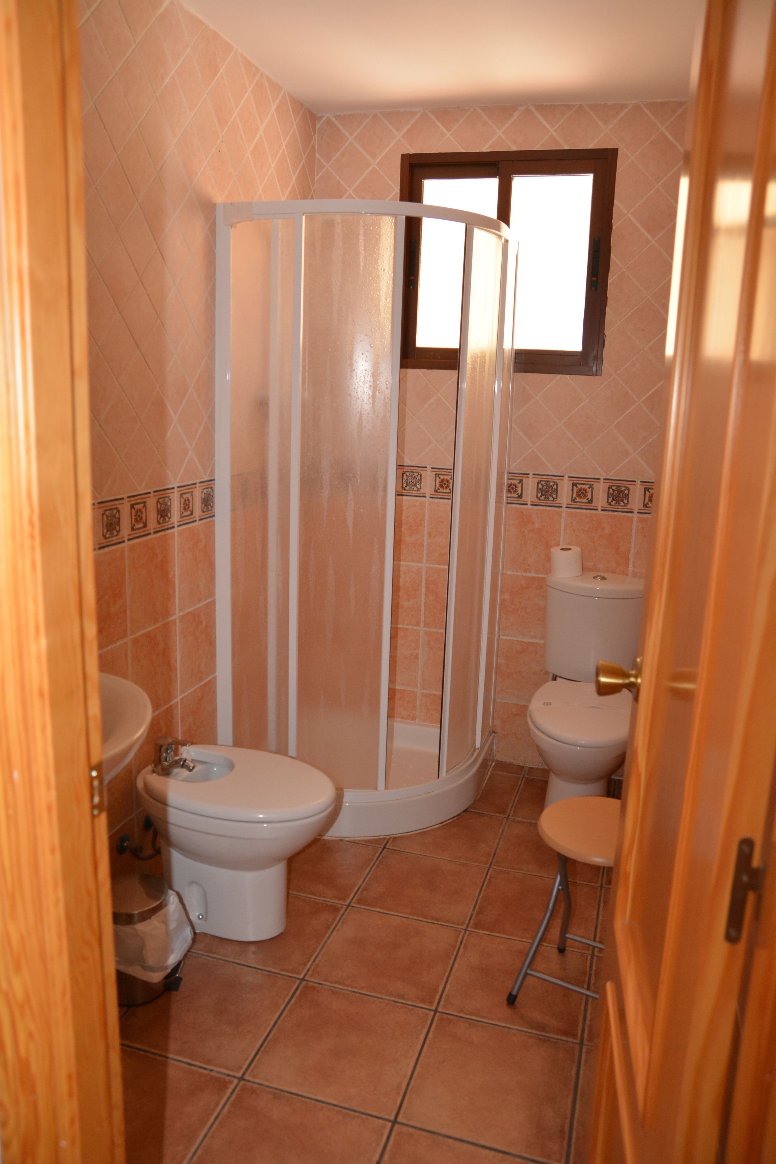 Un bagno con cabina doccia, due servizi igienici e un lavandino.