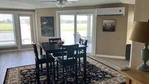 Un coin repas avec une table et des chaises, un ventilateur de plafond et une vue à travers la porte vitrée.