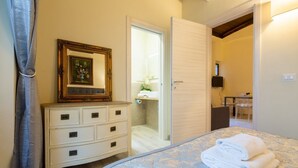 Un dormitorio con cama, cómoda, espejo y puerta que da al baño.