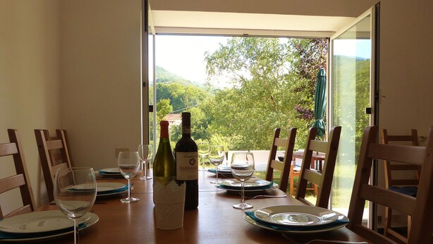 A dining table with wine glasses, a bottle of wine, and plates set for a meal. - Family Friendly Farmhouse -  Secluded 2 acres with Private Pool & Stream (Sassello)