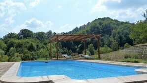 A rectangular swimming pool with a wooden pergola and lounge chairs in the background. - Family Friendly Farmhouse -  Secluded 2 acres with Private Pool & Stream (Sassello)