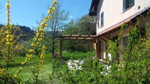 A house with a wooden pergola in the garden, surrounded by greenery and a clear sky. - Family Friendly Farmhouse -  Secluded 2 acres with Private Pool & Stream (Sassello)