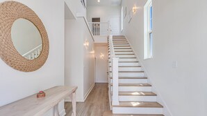 A staircase with white steps and a wooden handrail, leading to a landing with a white railing and a door.