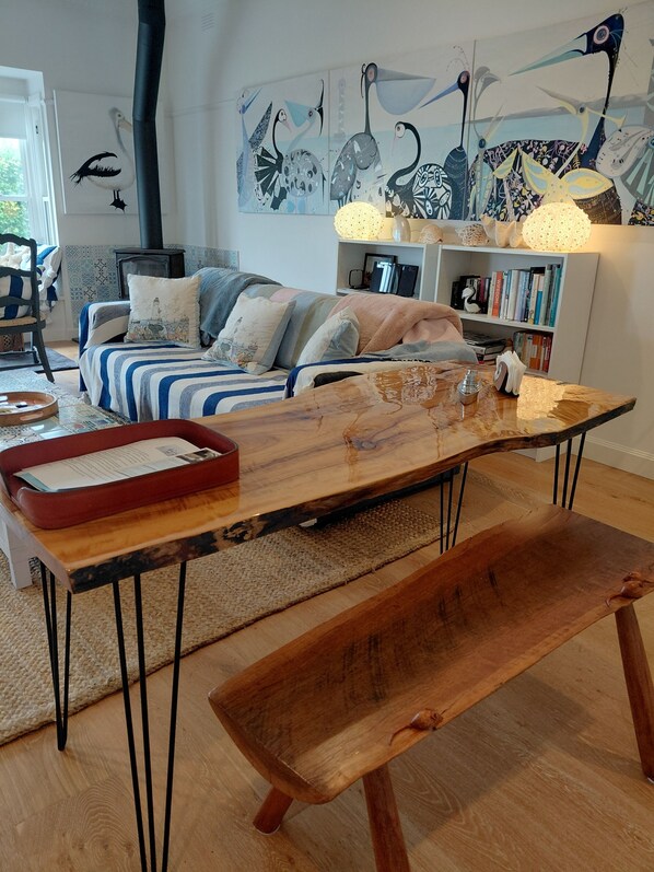 A cozy living room with a sofa, a wooden coffee table, a bench, a bookshelf, and wall art.
