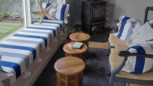 Um quarto acolhedor com cama, sofá, uma pequena mesa de madeira, lareira e janela com vista para um jardim.