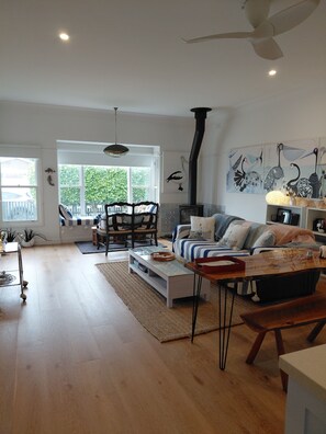 Een ruime woonkamer met een groot raam, een bank, een salontafel en een open haard.