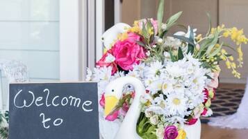 A welcome sign and a decorative swan vase with flowers.
