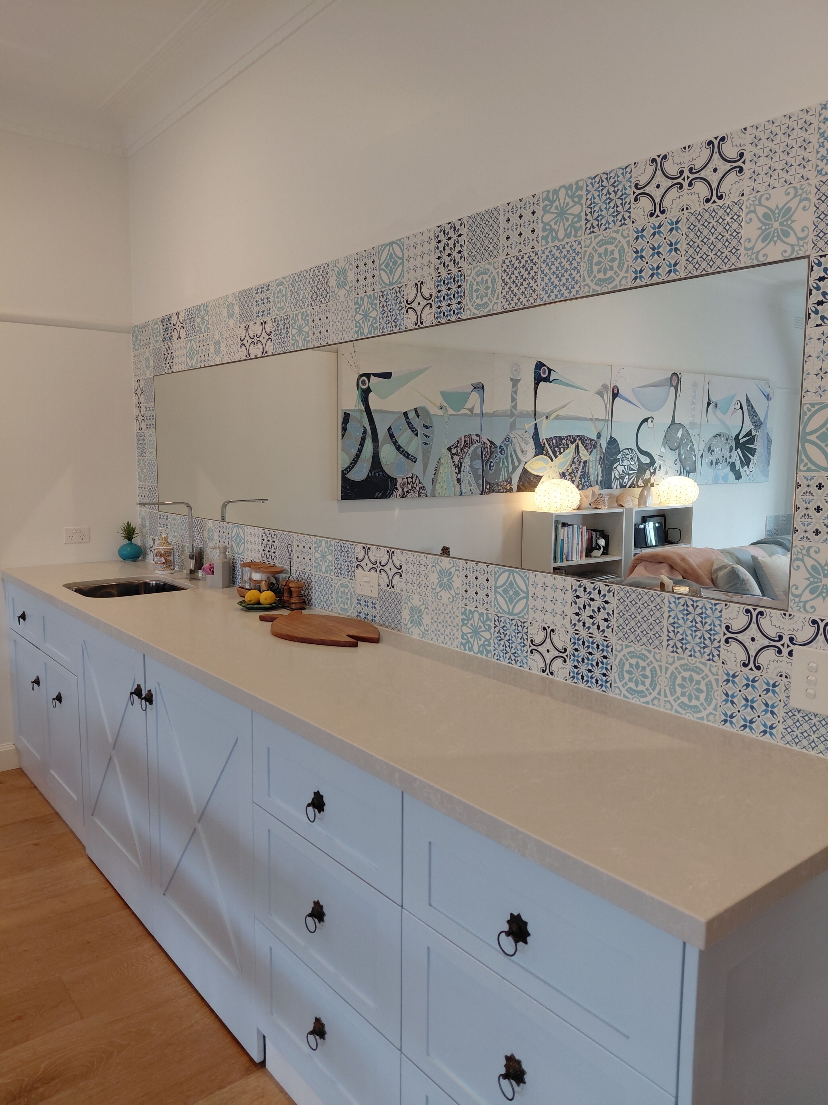 A modern kitchen with a white countertop, a sink, and a decorative wall with a blue and white pattern.