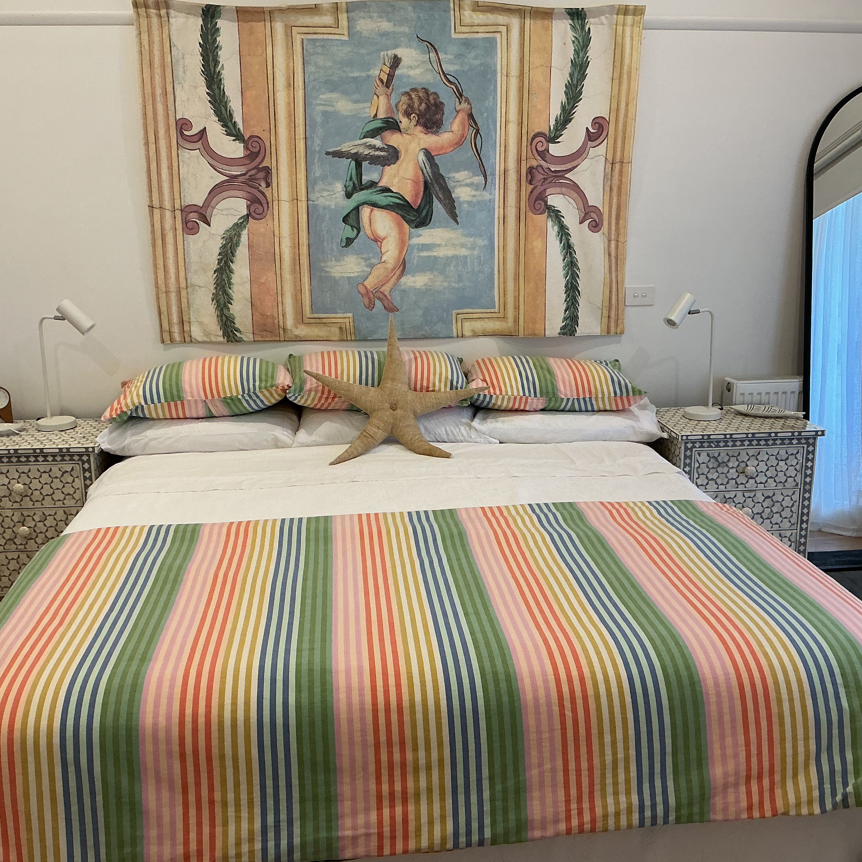A bed with a starfish decoration, striped pillows, and a colorful striped bedspread.
