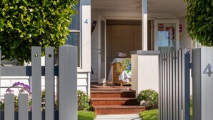 Uma casa residencial com varanda da frente, portão de madeira e caminho que leva à entrada.