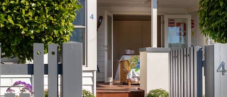 Ein Wohnhaus mit Veranda, einem Holztor und einem Weg zum Eingang.