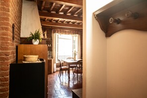 A wooden dining table with chairs, a potted plant, and a basket on a black cabinet. - Suite nell´ Anfiteatro Romano (Lucca)