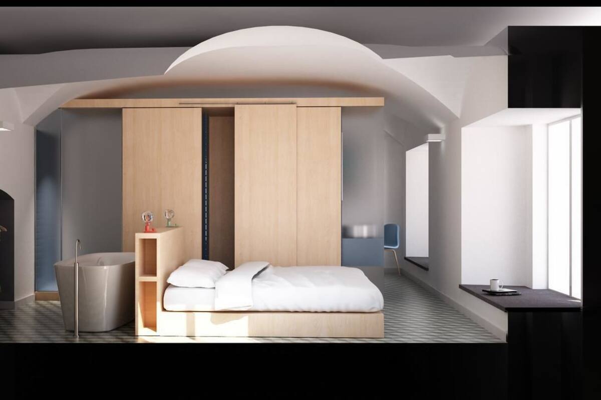 A modern bedroom with a bed, a wardrobe, a small table, and a mirror.
