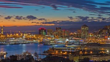 A cityscape at dusk with a waterfront, illuminated buildings, and a prominent tower.