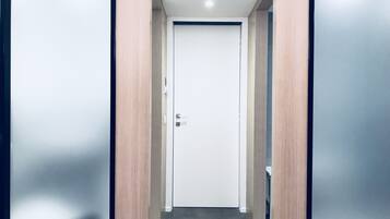 A hallway with a closed door at the end, flanked by two mirrored panels on the walls.