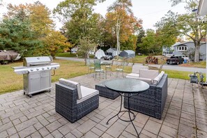 Une terrasse extérieure équipée d’un barbecue, de sièges et d’une table.