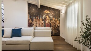 Una sala de estar moderna con un sofá modular, un mural grande en la pared y una escalera que lleva a un nivel superior.