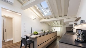Una cocina moderna con una isla central, vigas de madera, tragaluces y una cafetera.
