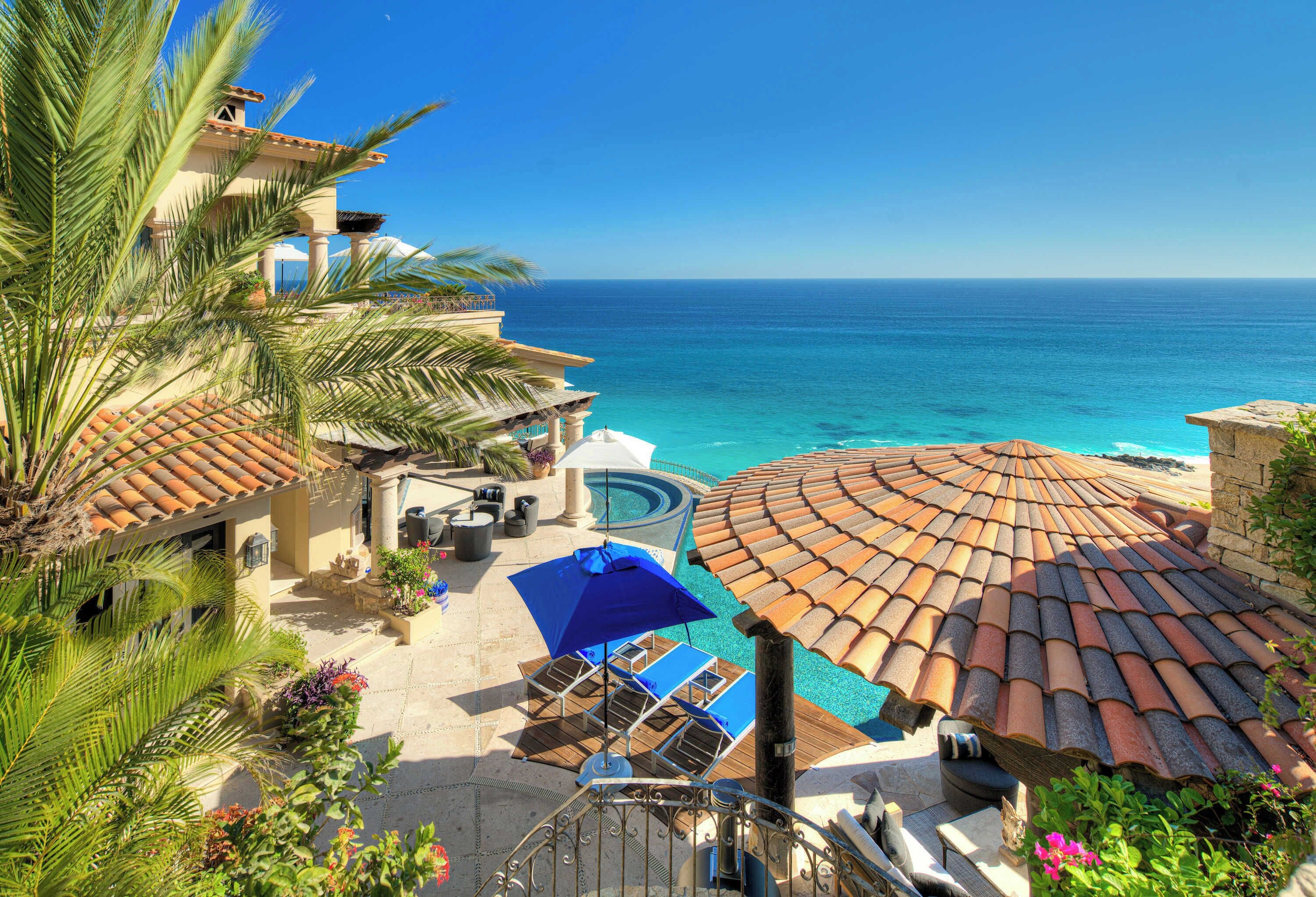 Un complexe hôtelier doté d’une piscine, de parasols et offrant une vue sur l’océan.