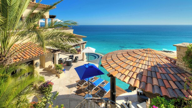 Un resort con piscina, sombrillas y vista al océano.