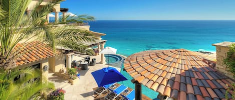 A resort with a pool, umbrellas, and a view of the ocean.