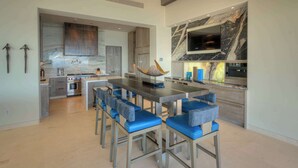 Una cocina moderna con una isla grande, taburetes de bar y un televisor montado sobre la encimera.