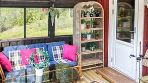 Un rincón acogedor con una mesa de vidrio, sillas de mimbre y una estantería con plantas.