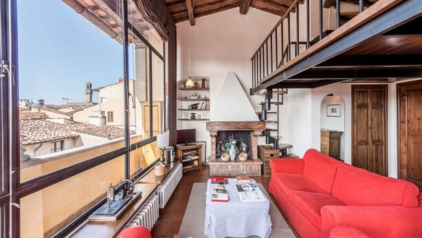 Ein Wohnzimmer mit einem roten Sofa, einem Kamin und Blick auf die Stadtlandschaft.