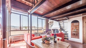 Ein geräumiger Wohnbereich mit einem Holztisch, roten Sofas und großen Fenstern mit Blick auf die Stadt.