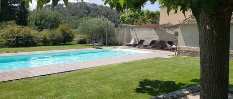 Une piscine avec des chaises longues et un mur de pierre en arrière-plan.