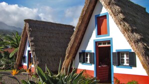 A traditional thatched-roof house with a red door and blue trim. - Home for Nature Tourism, Madeira Island LAURISHOUSE, Nature and Sea (Prazeres)