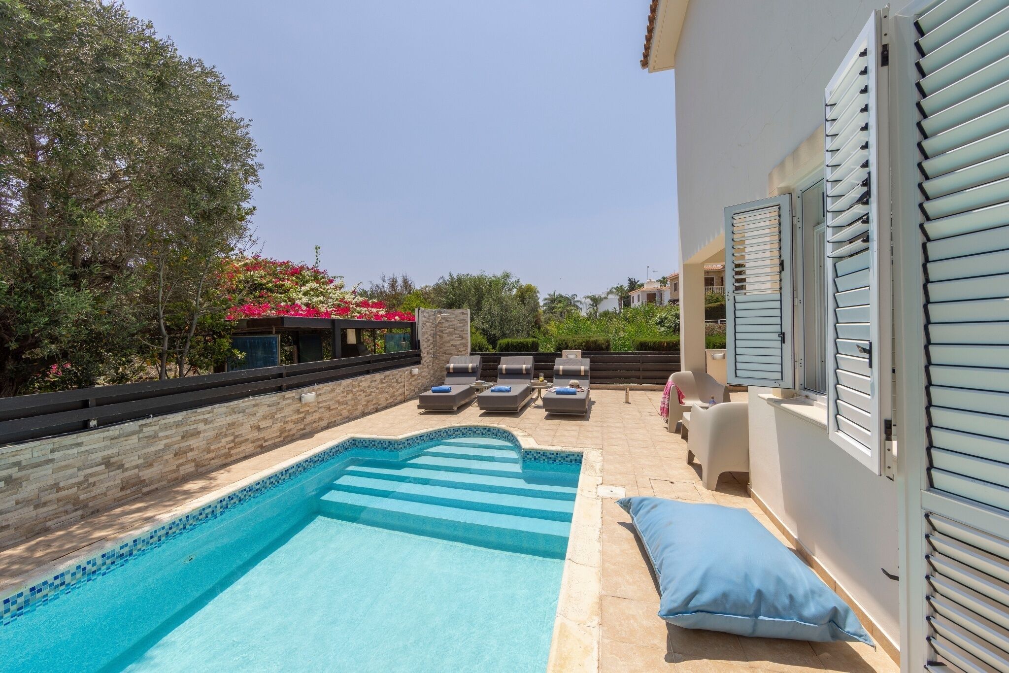 A swimming pool with lounge chairs and a stone wall.