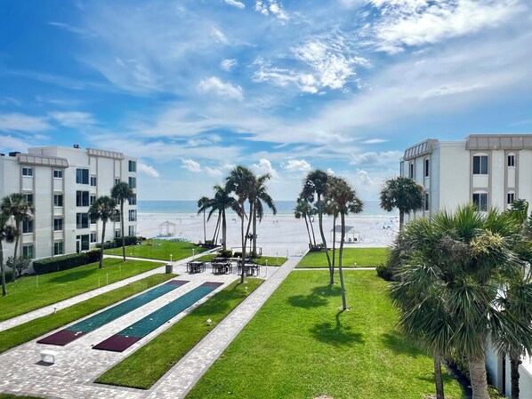 A resort with a pool area, palm trees, and a view of the beach.