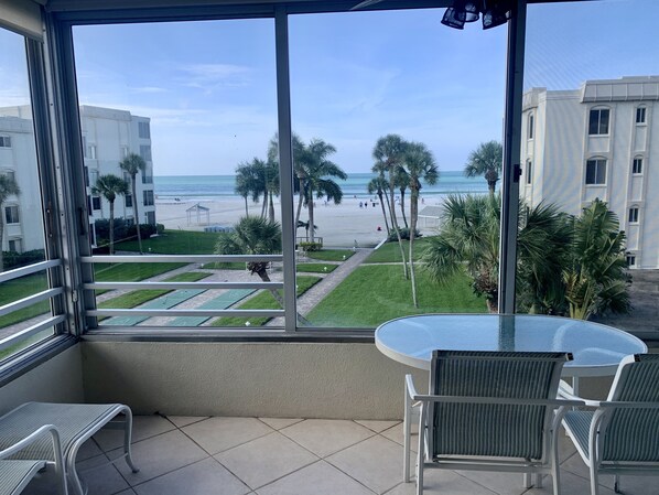 Un balcone con vista sulla spiaggia, palme e area piscina.