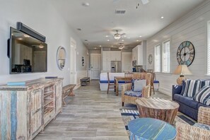 A spacious living room with a large mirror, a dining area, and a kitchen in the background.