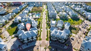 An aerial view of a coastal residential area with uniform white houses, a central road, and a beach in the background. - Pet-Friendly Condo w/ Central Location+Resort-Like Amenities@Cinnamon Shore (Port Aransas)