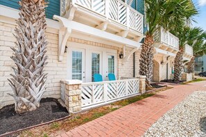 A beachfront property with a two-story building, a balcony with white railings, and palm trees. - Pet-Friendly, Stylish Condo w/ Cinnamon Shore Pools, Dining & More! (Port Aransas)