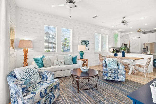 A living room with a sofa, chairs, a coffee table, and a kitchen in the background. - Pet-Friendly, Stylish Condo w/ Cinnamon Shore Pools, Dining & More! (Port Aransas)