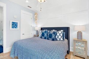 A bedroom with a bed, bedside lamps, a chandelier, a door, and a wall-mounted picture. - Pet-Friendly, Stylish Condo w/ Cinnamon Shore Pools, Dining & More! (Port Aransas)