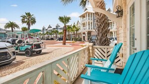Ein Strandhotel mit überdachter Terrasse, Sitzgelegenheiten im Freien und parkenden Fahrzeugen.