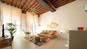 Una sala de estar con un sofá, dos otomanas, una planta en maceta, un escritorio y una silla.